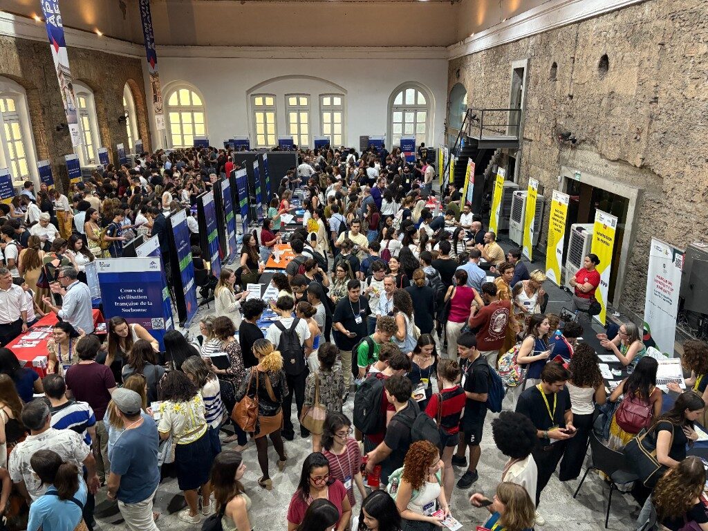Wide crowd shot inside the EXPO venue with French university banners and packed exhibitor floor
